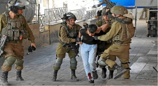 Soldados israelíes detienen a un adolescente palestino en Hebrón, durante las protestas por la operación en Nablús. (Moshad SHAWER | AFP)