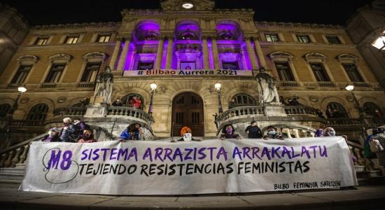 Colectivos de mujeres migradas y racializadas han portado la pancarta hasta un Ayuntamiento iluminado para la ocasión. (Aritz LOIOLA/FOKU)